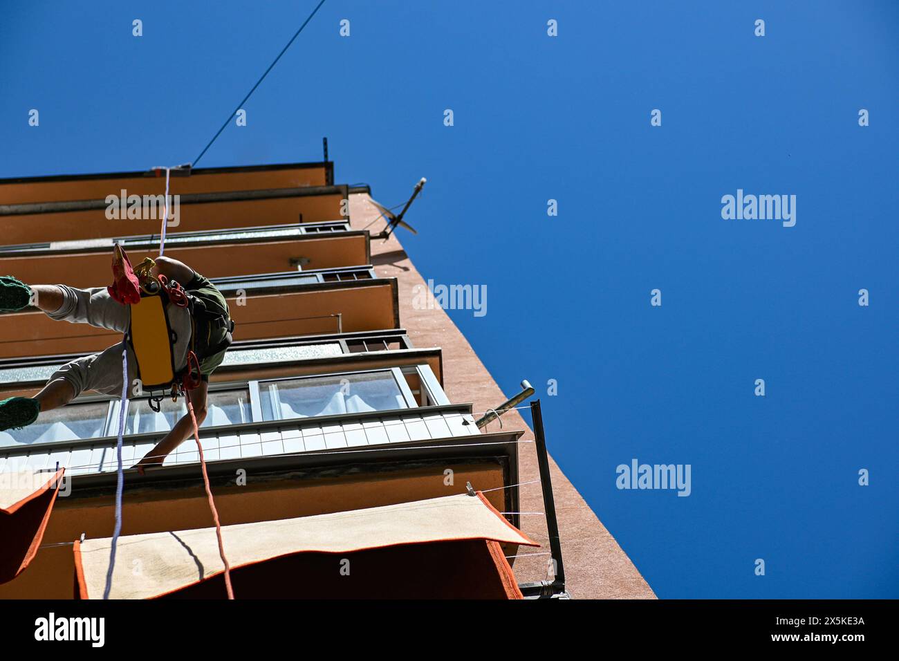 high-rise work on an apartment building. A construction worker inspects the condition of an apartment building for planned reconstruction using climbi Stock Photo