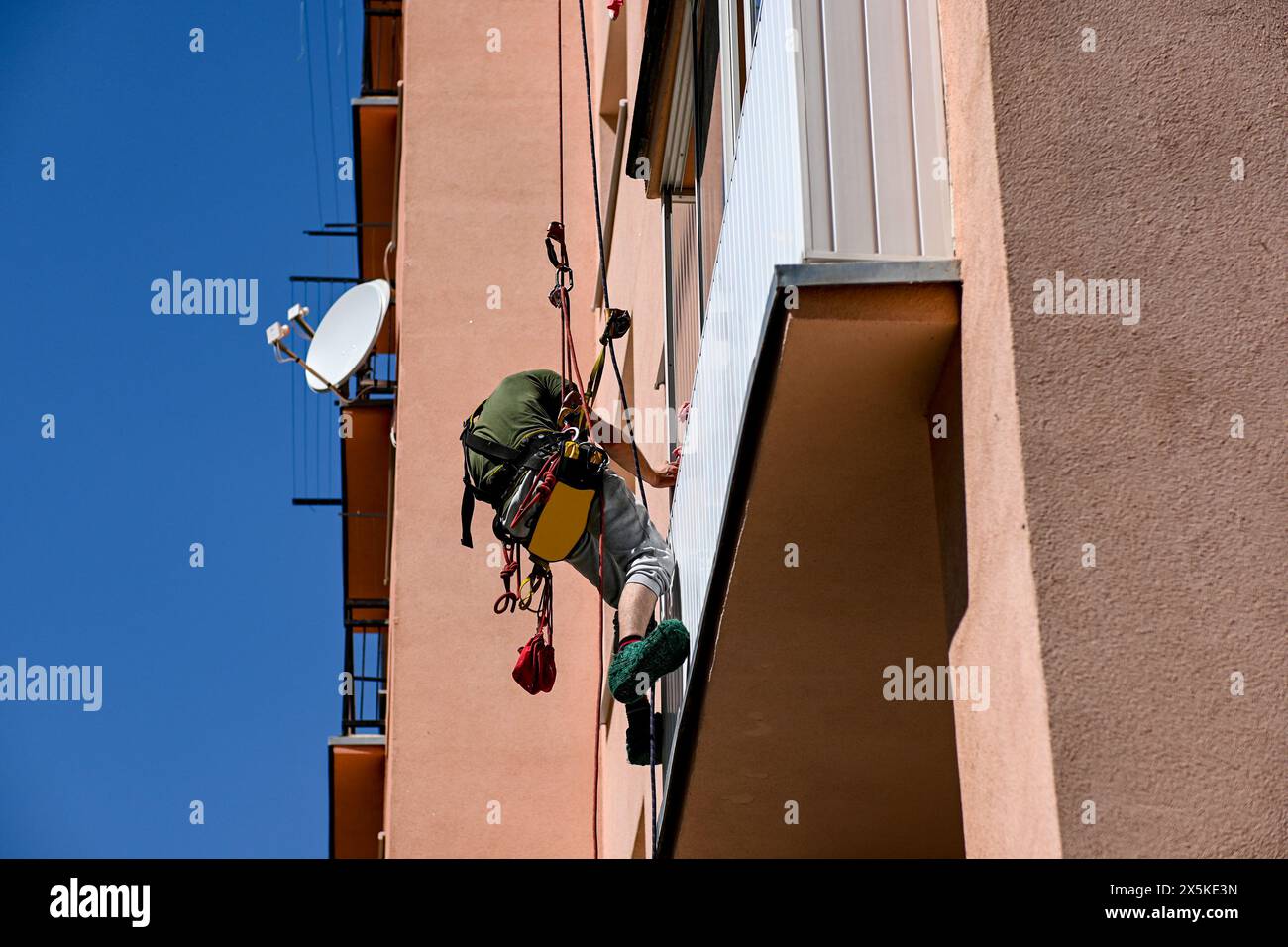 high-rise work on an apartment building. A construction worker inspects the condition of an apartment building for planned reconstruction using climbi Stock Photo