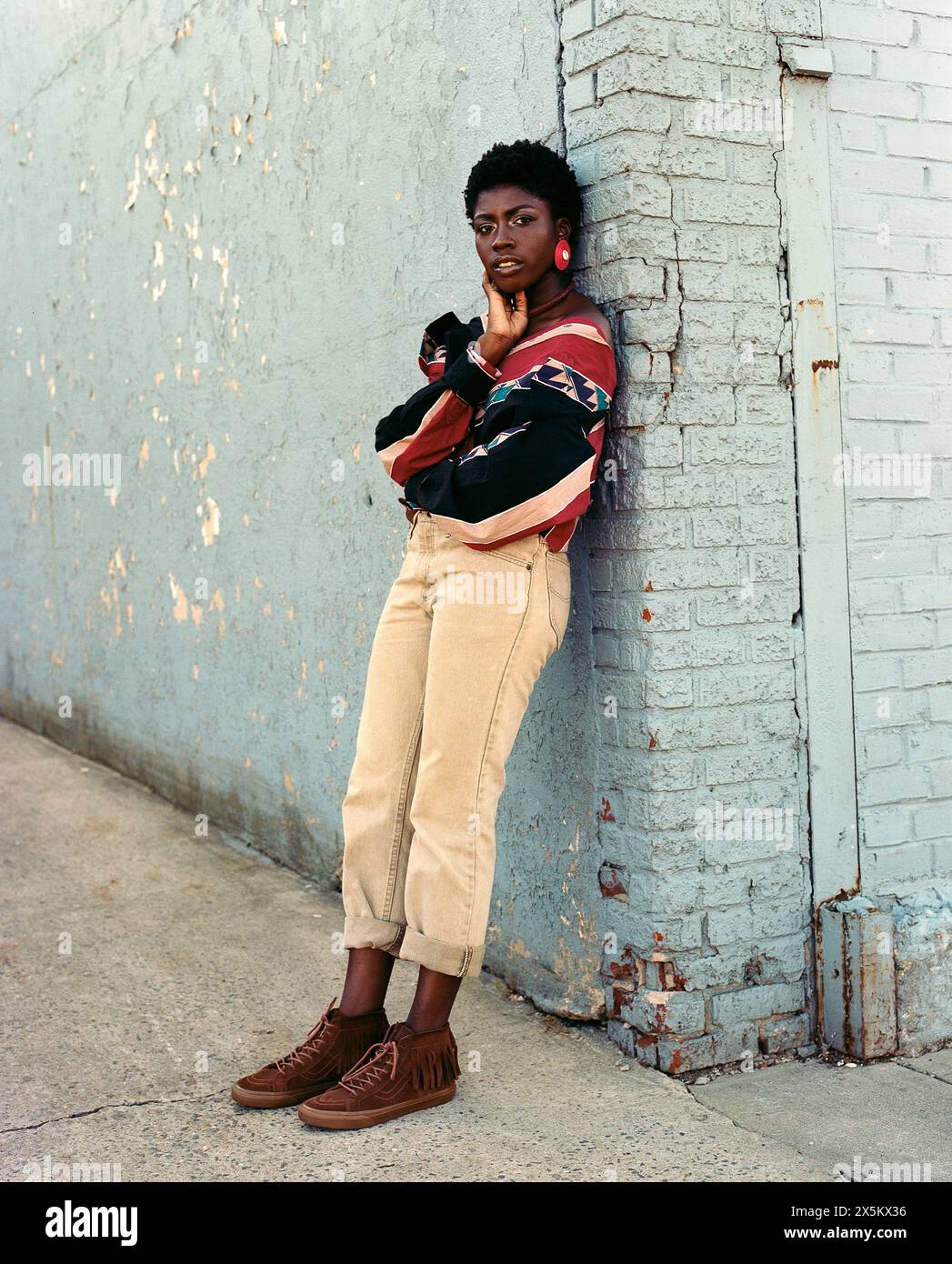 USA, New York, Portrait of young fashionable woman leaning against old building Stock Photo
