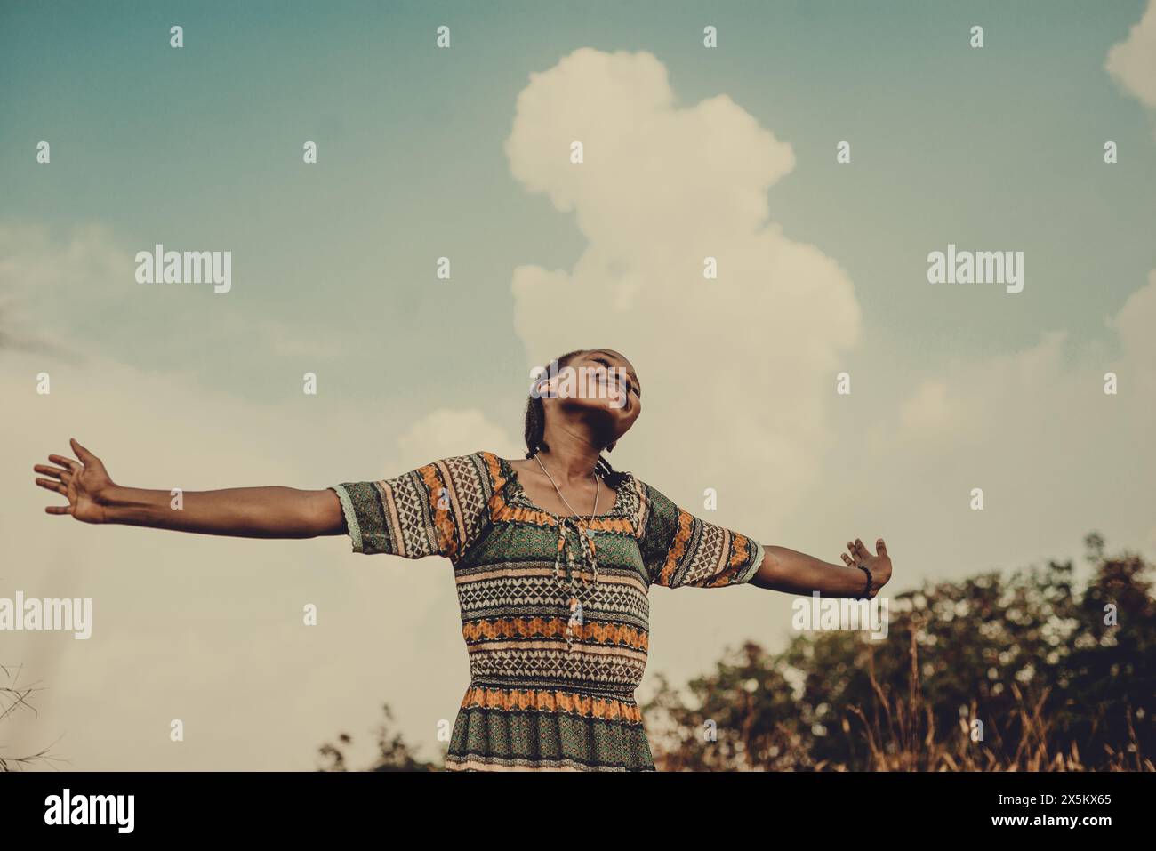 Nigeria, Delta state, Smiling woman with arms outstretched against sky Stock Photo