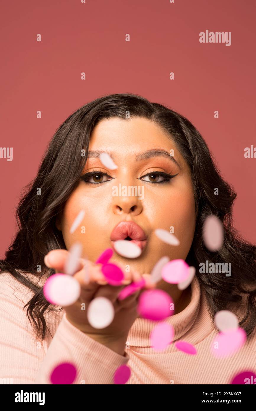 Studio portrait of woman blowing confetti Stock Photo - Alamy