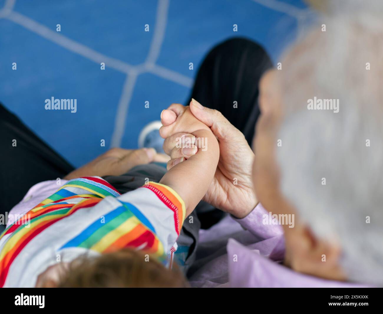 Close-up of boy and grandfather holding hands Stock Photo