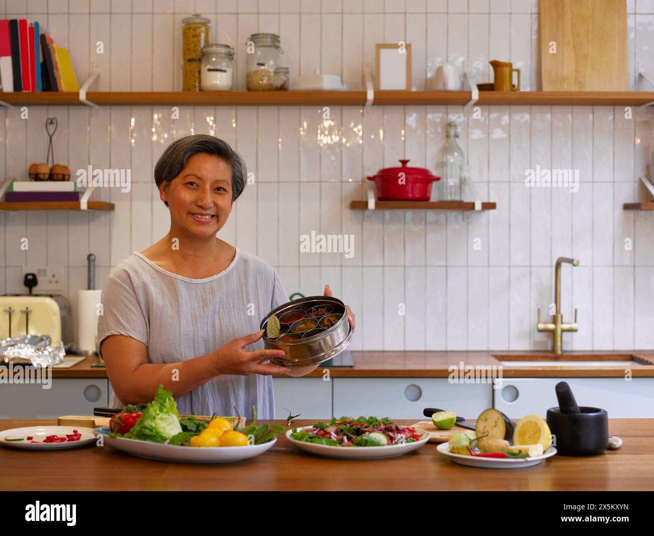 Portrait of woman showing freshly prepared food in kitchen Stock Photo