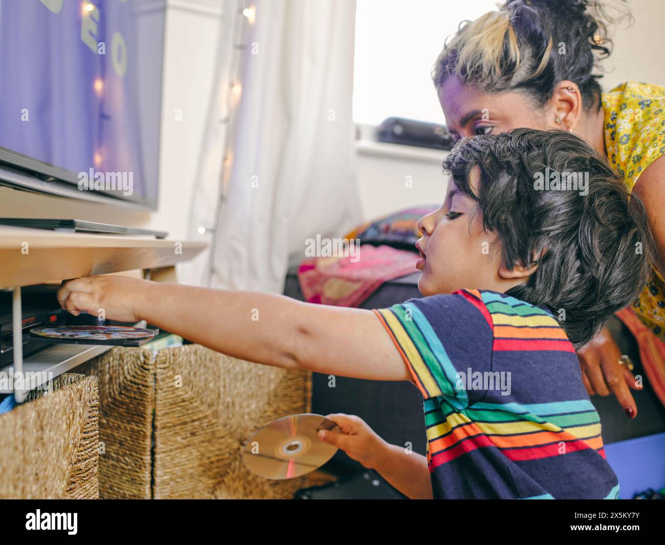 Mother and son putting DVDs into DVD player Stock Photo - Alamy