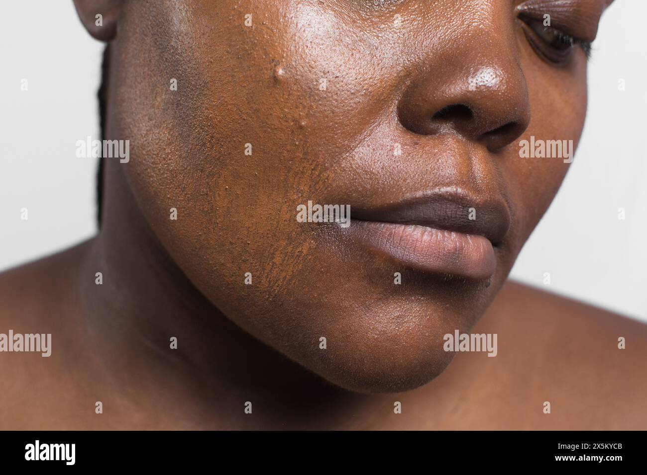 Brown skinned woman applying foundation with makeup brush, dark skin