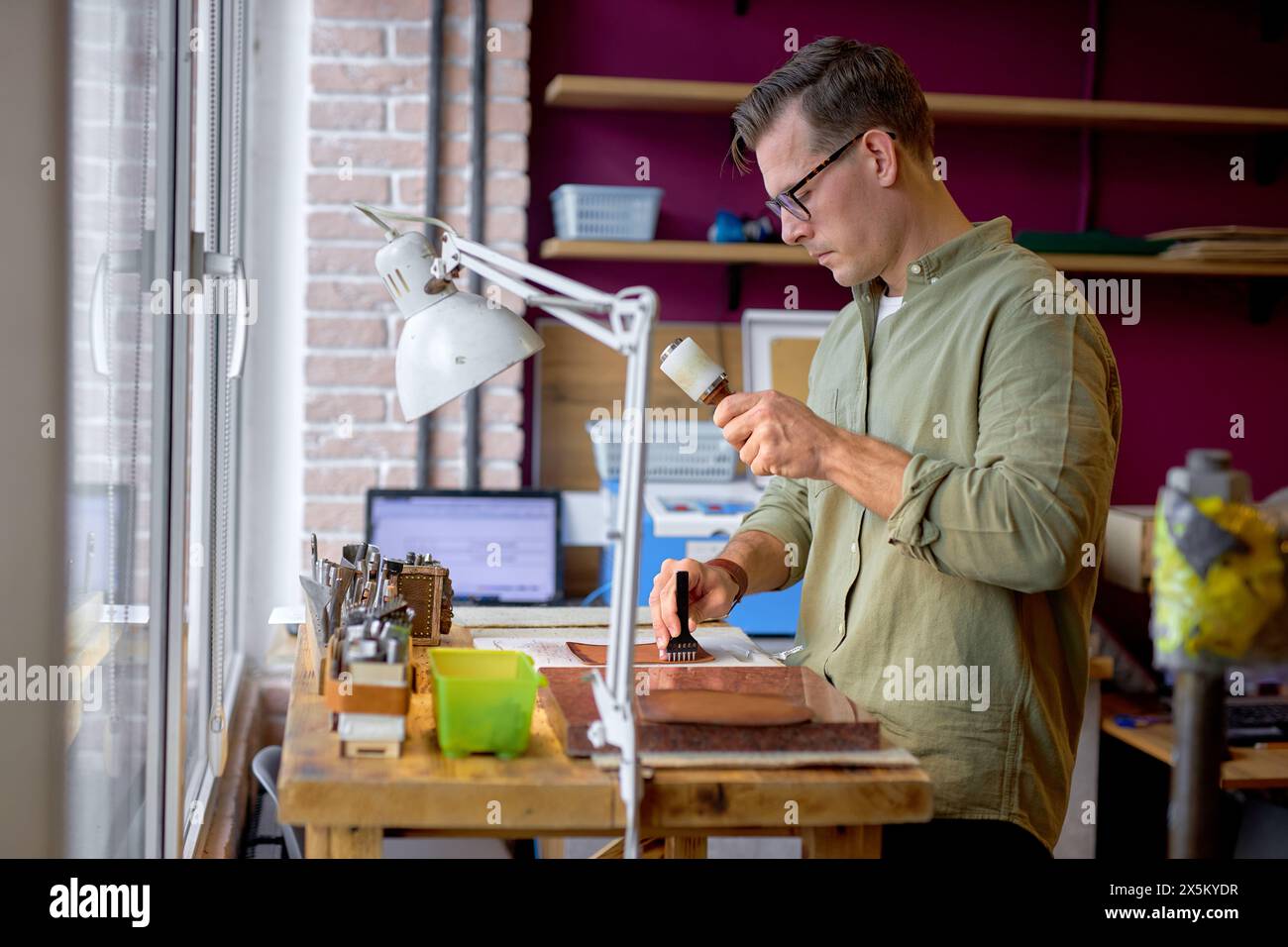 young skilled artisan in stylish green shirt working with Leather mauls.hobby, job, profession, occupation, close up side view shot Stock Photo