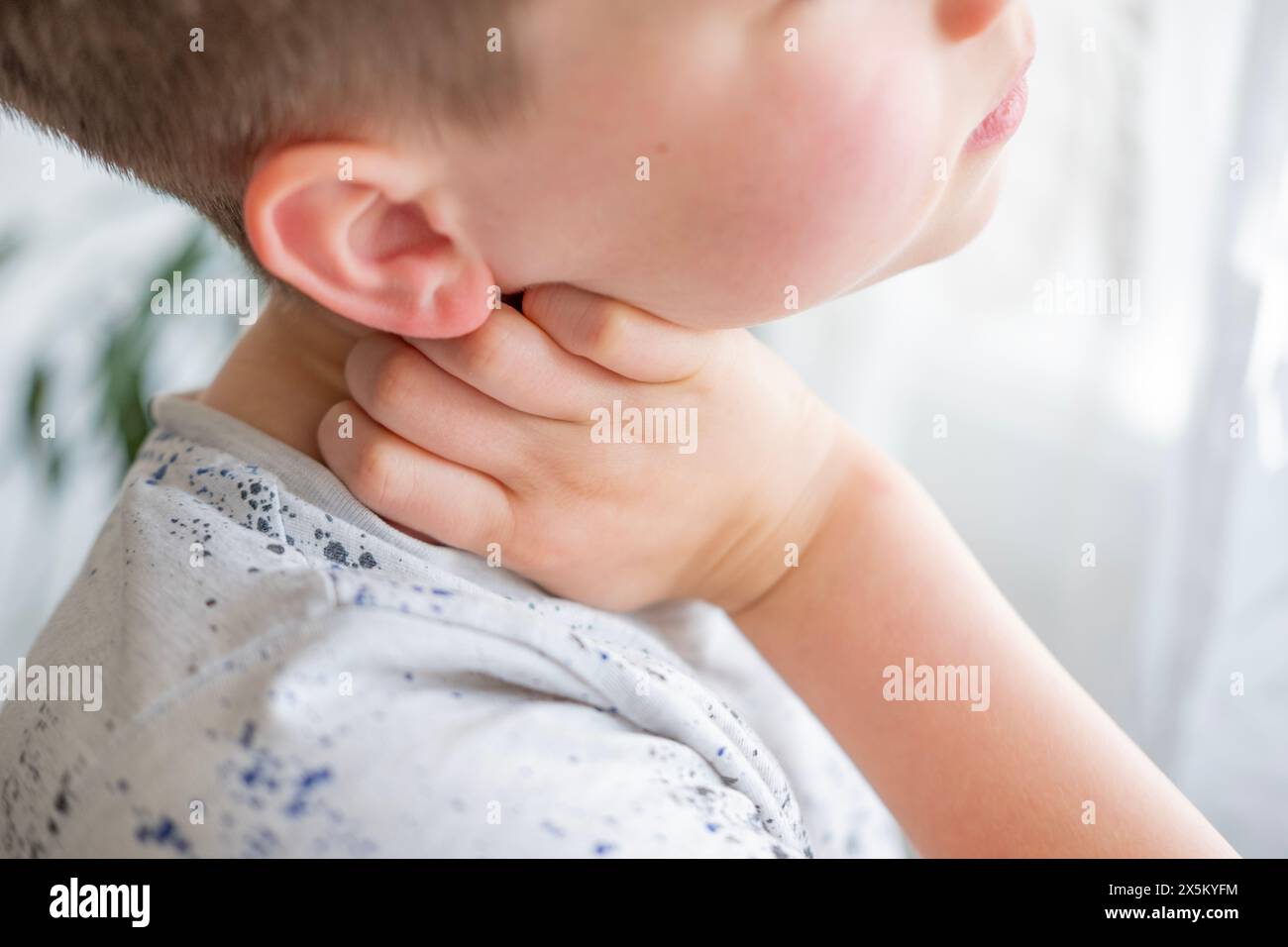 close-up neck, caucasian child patient holding affected area, experiencing throat pain, various causes, medical attention and treatment for condition, Stock Photo
