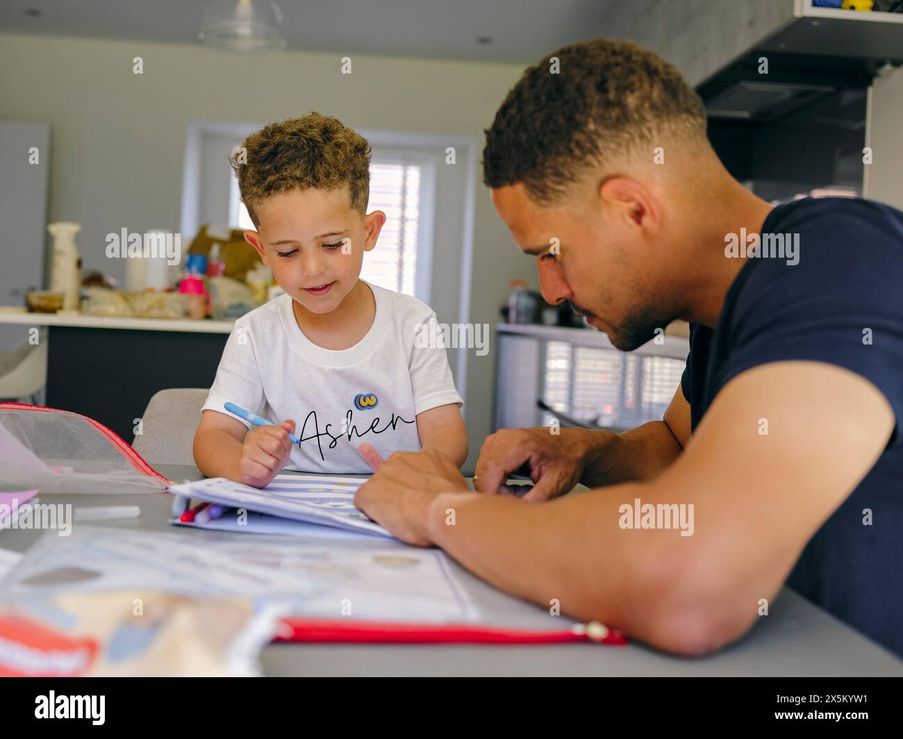 Father assisting son doing homework at home Stock Photo