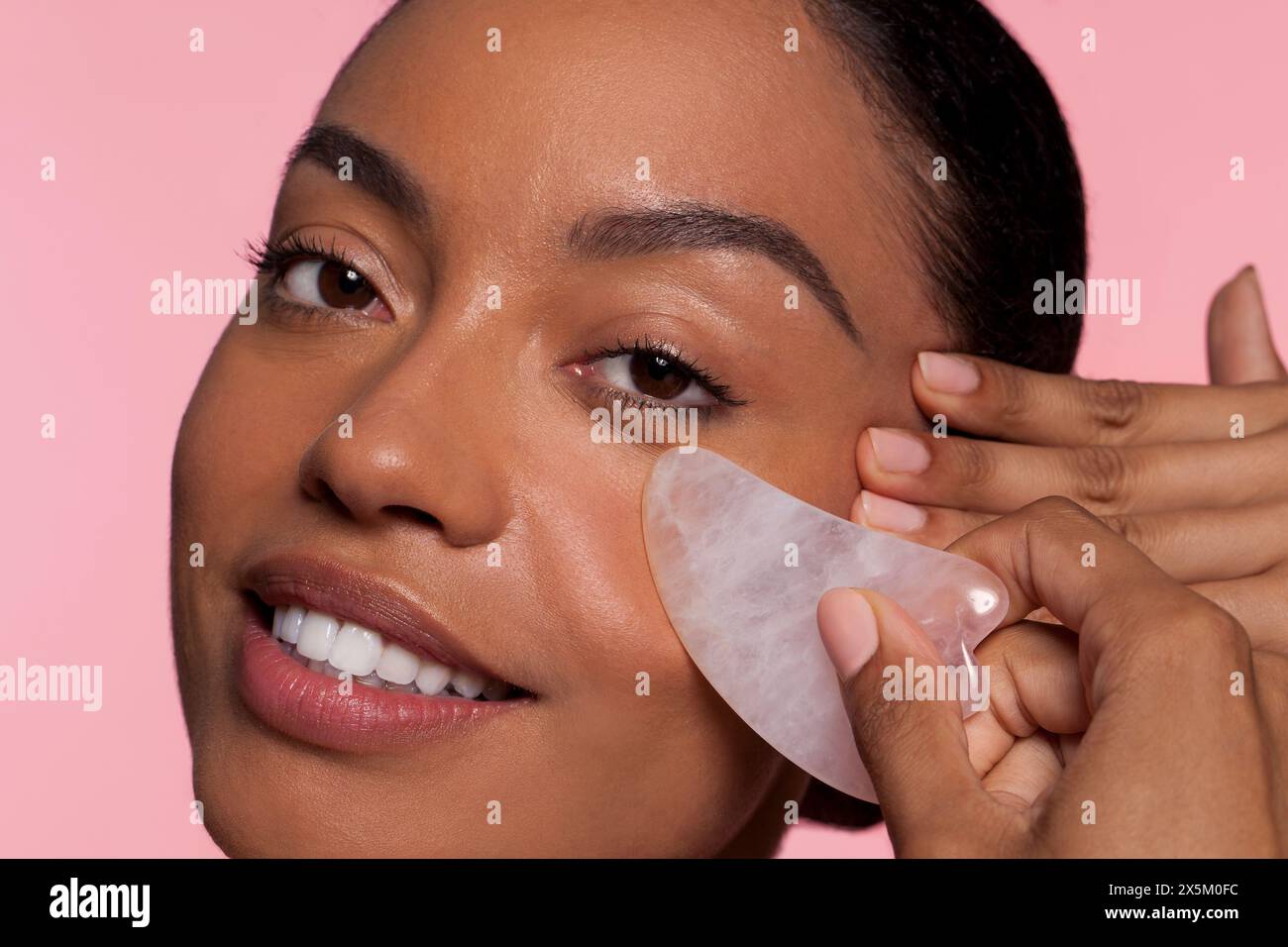 Studio portrait of beautiful woman applying under eye patch Stock Photo