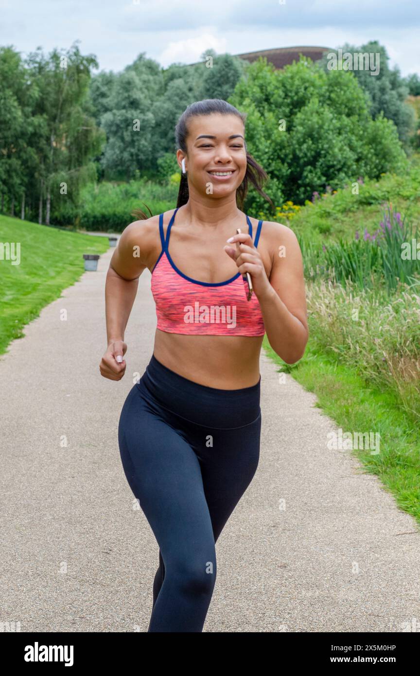 Smiling woman jogging with smart phone Stock Photo