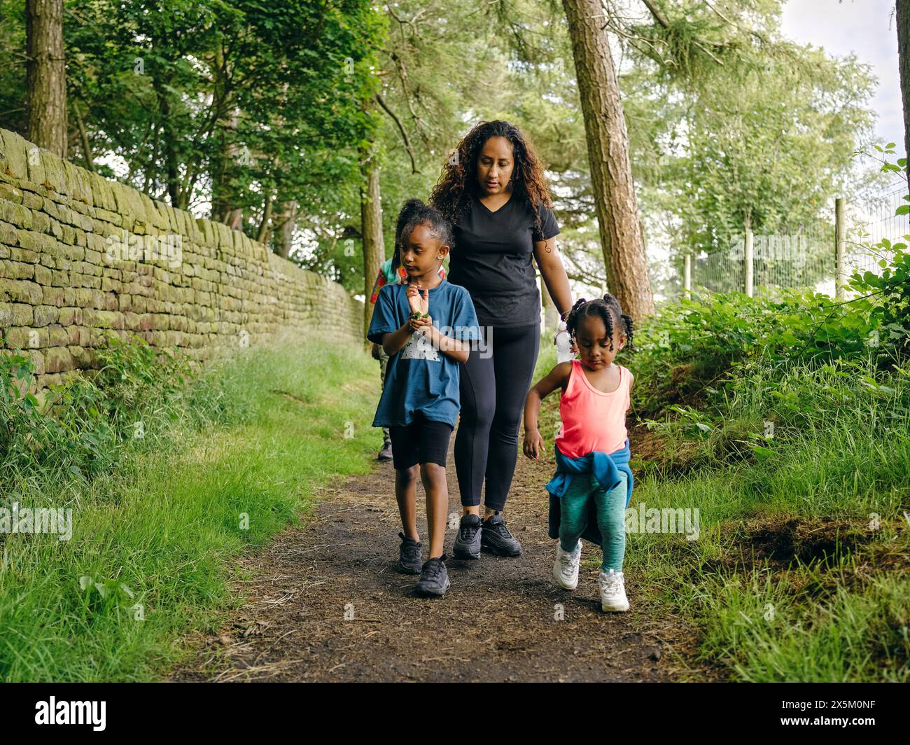 Mother with daughters walking on footpath through forest Stock Photo