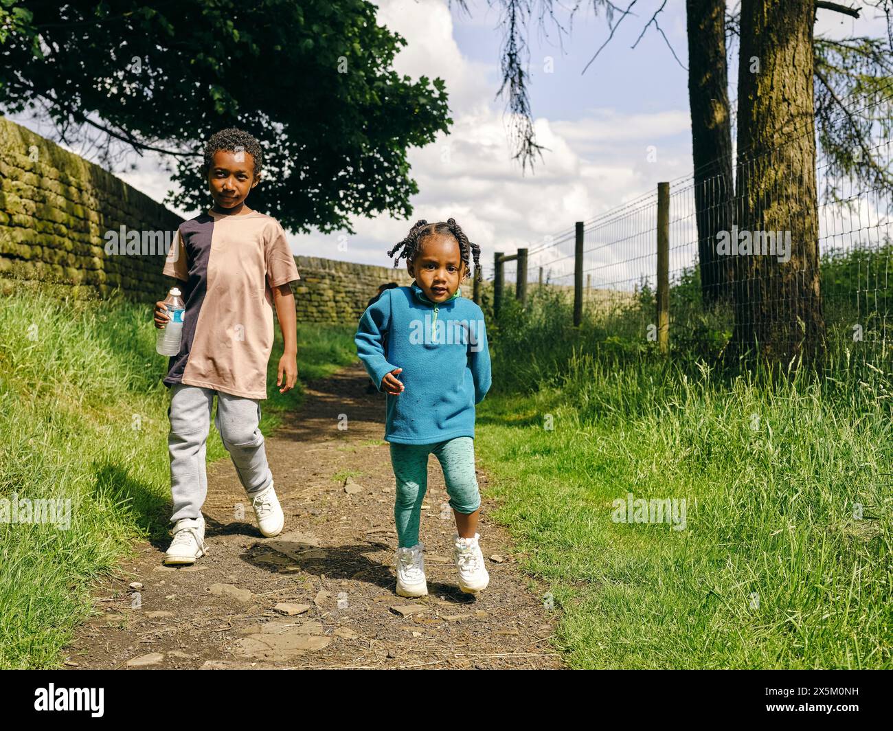 Brother and sister walking on footpath Stock Photo - Alamy