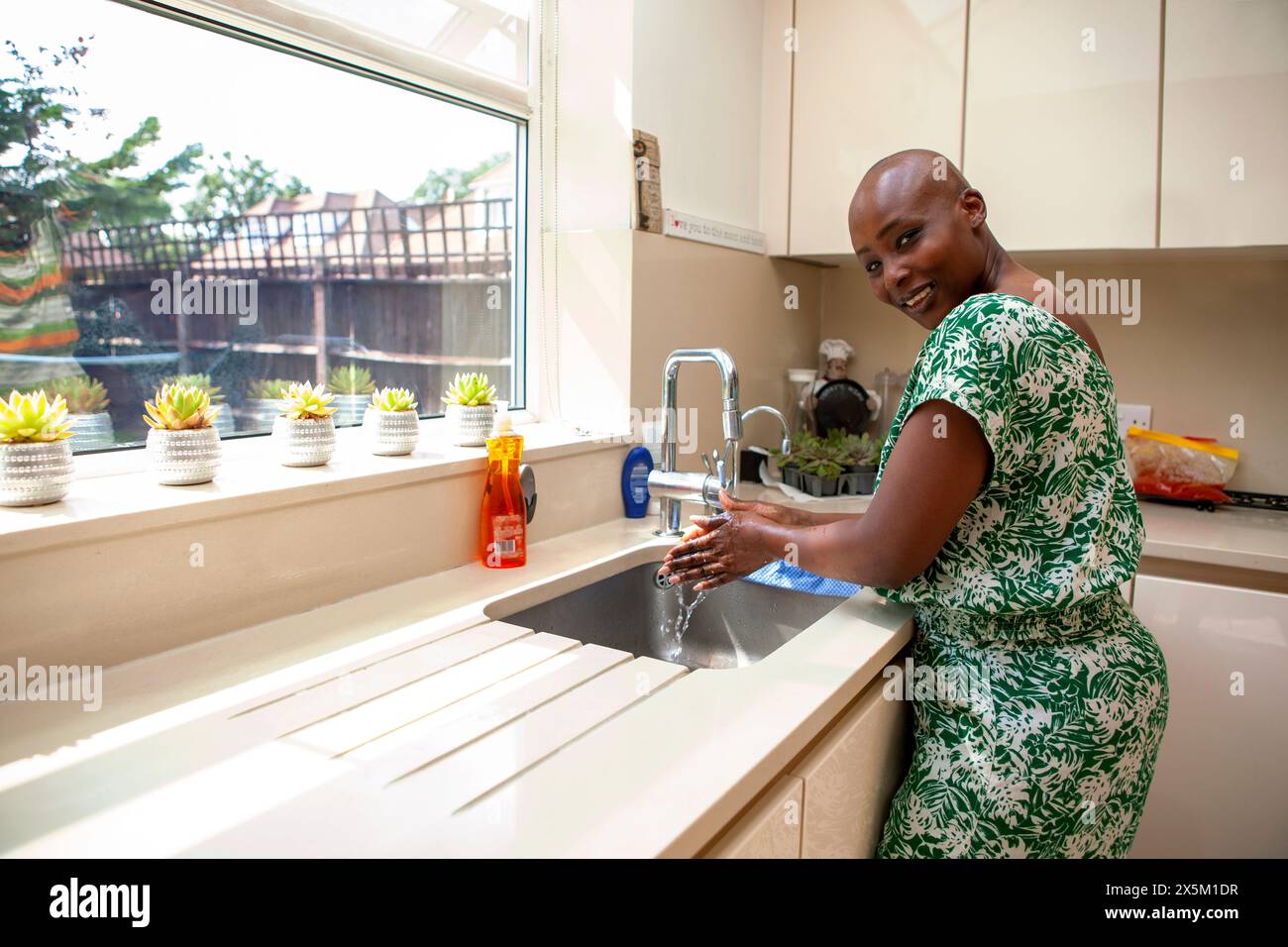 Woman washing hands in kitchen sink stock photo alamy