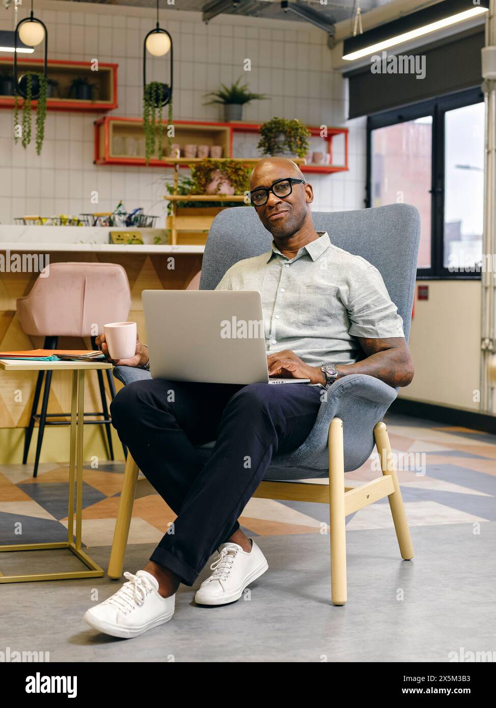 Man using laptop in office cafeteria Stock Photo