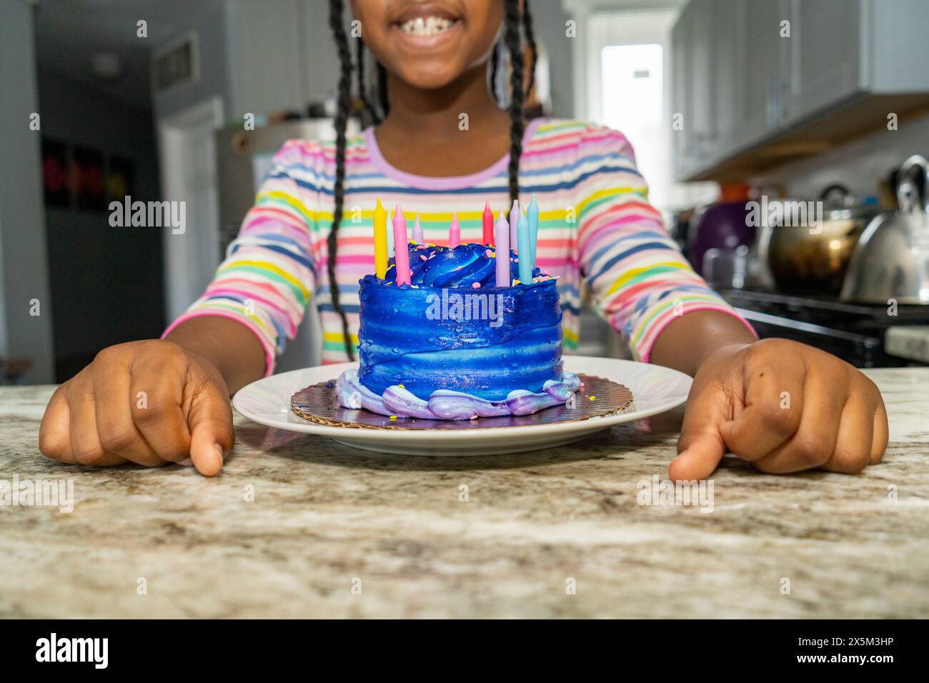 Girl with blue birthday cake on kitchen counter Stock Photo - Alamy
