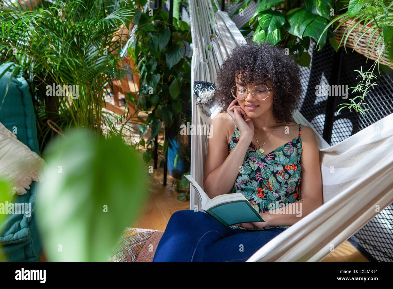 Woman sitting in hammock and reading book Stock Photo - Alamy