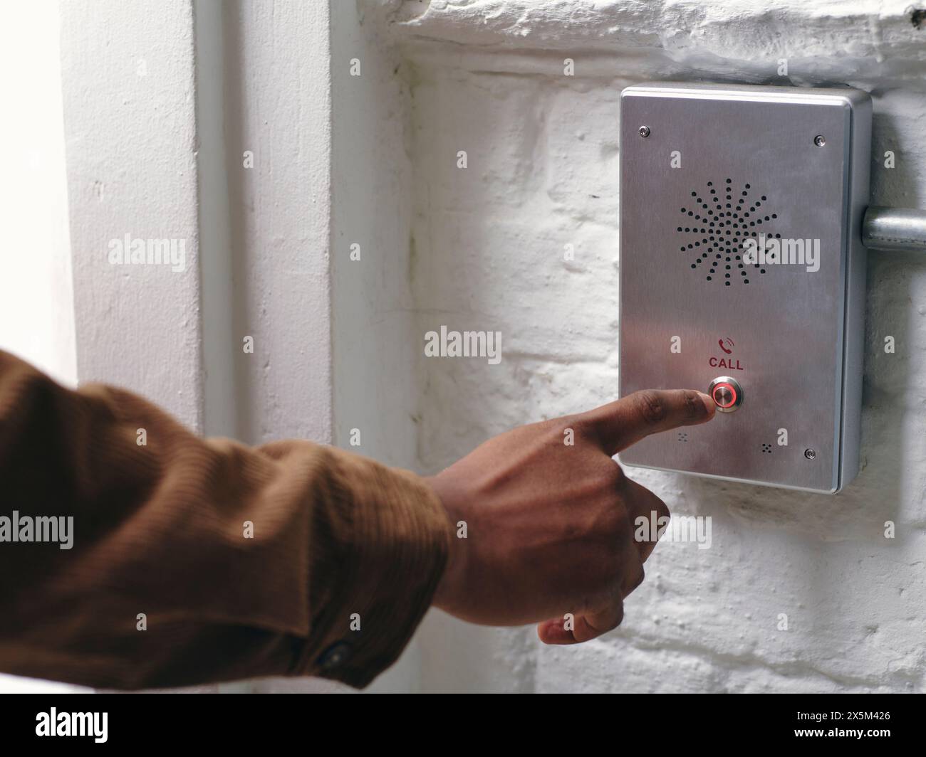 Close-up of mans hand pushing intercom button Stock Photo