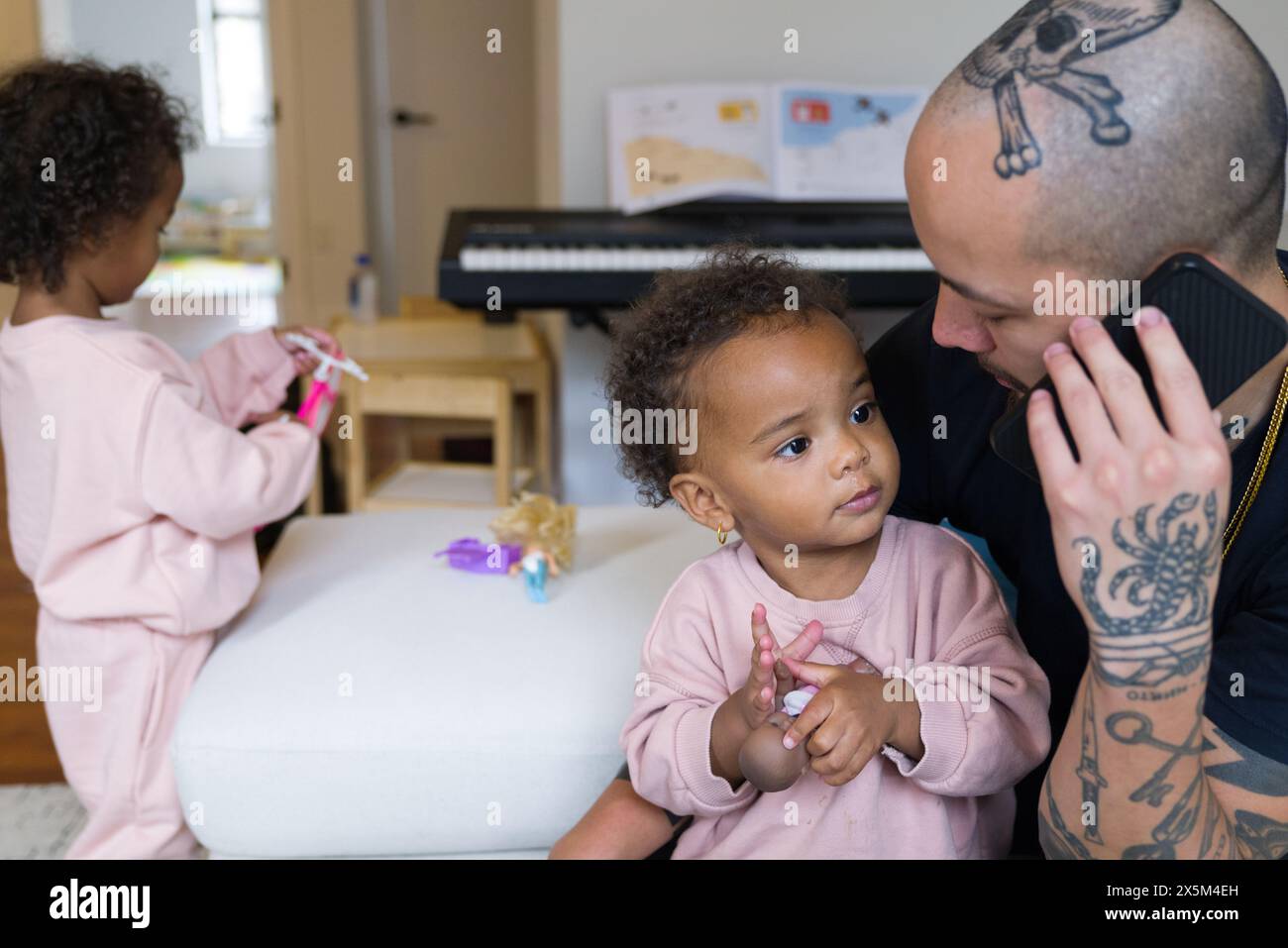 Father talking on phone and taking care of daughters Stock Photo