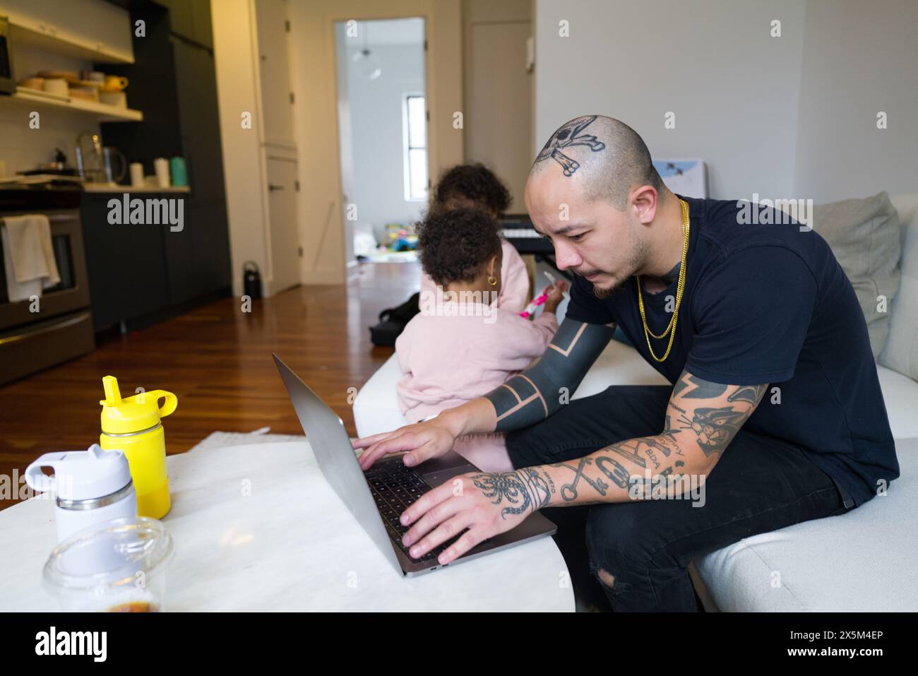 Father working on laptop while daughters playing Stock Photo