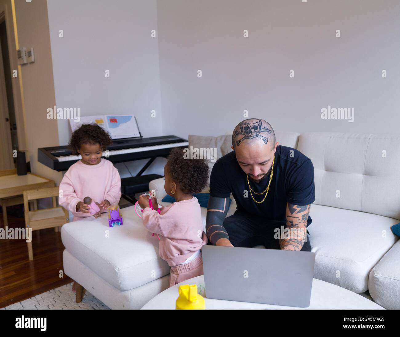 Father working on laptop while daughters playing Stock Photo