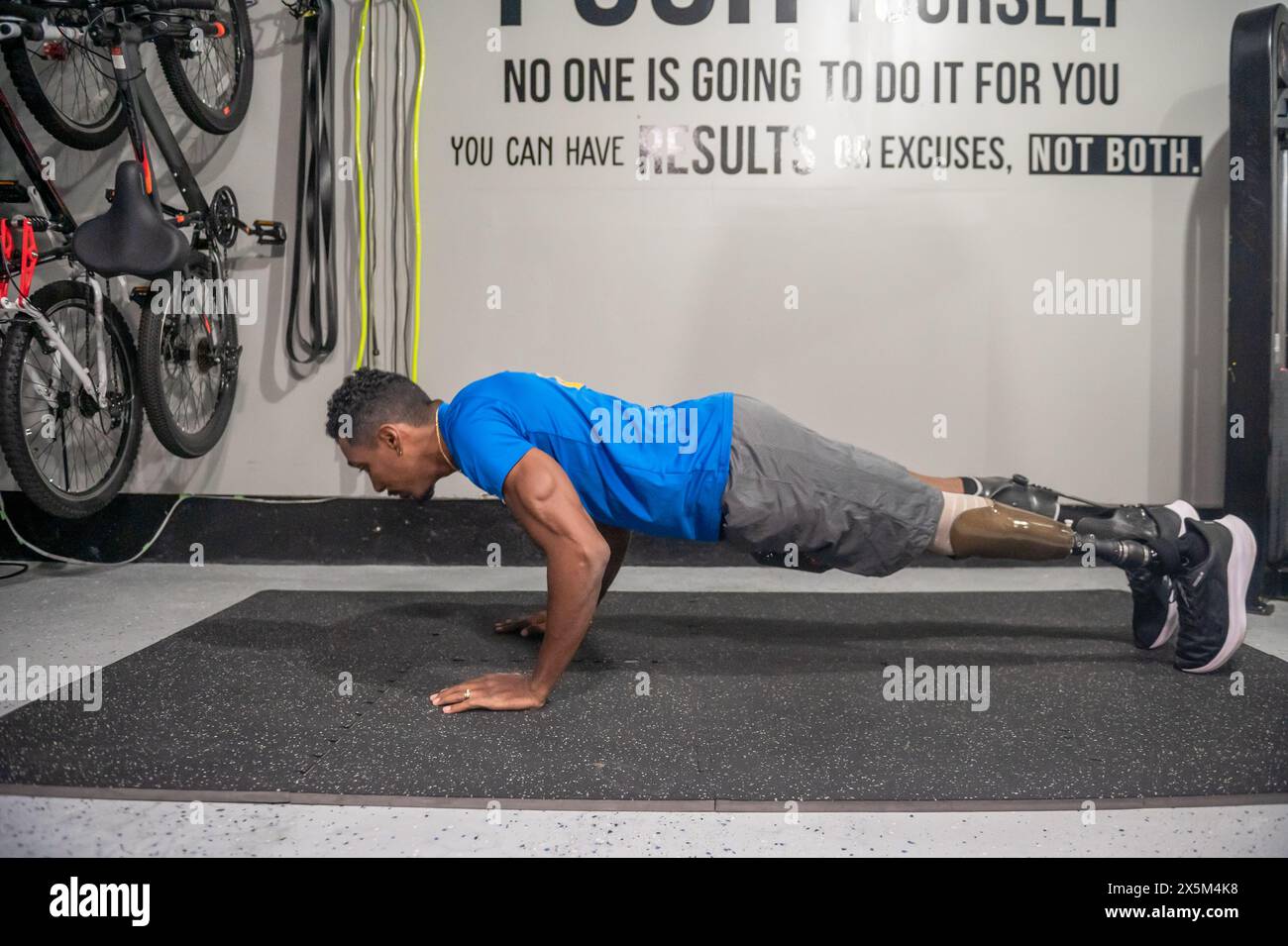 Man with prosthetic leg doing push-ups in gym Stock Photo
