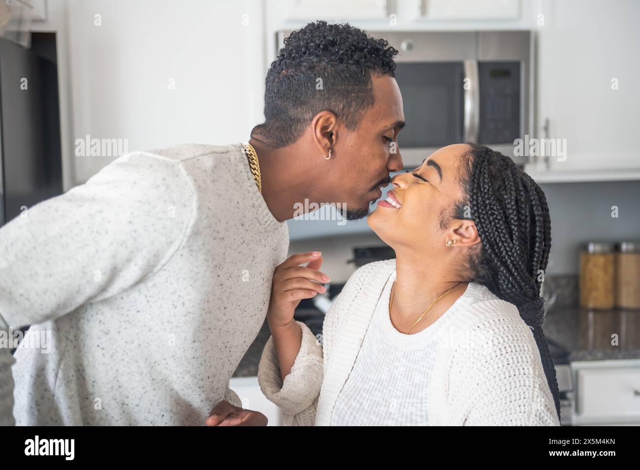 Smiling couple kissing in kitchen Stock Photo