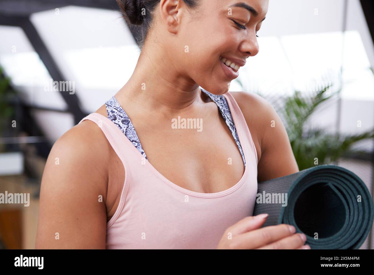 Smiling woman with exercise mat in pilates studio Stock Photo