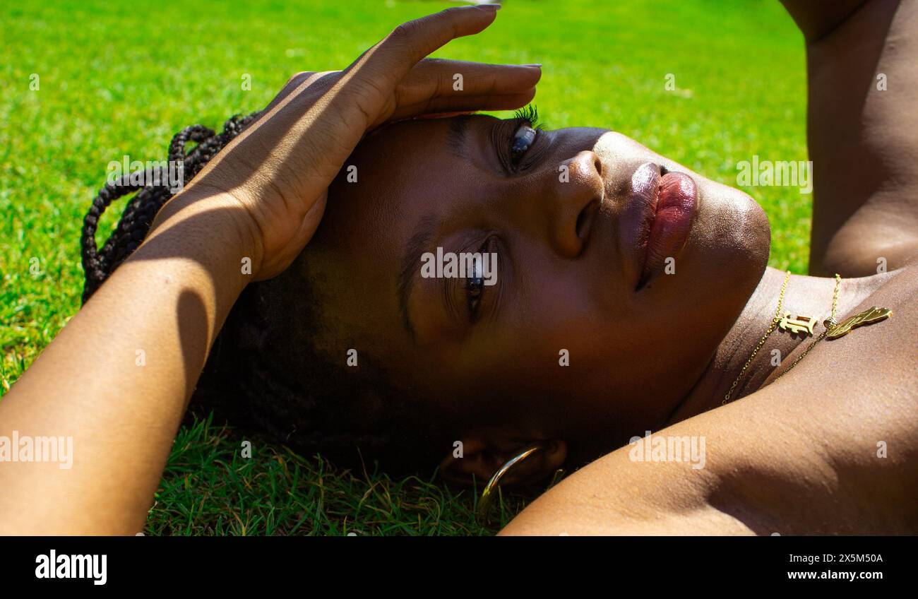 Portrait of young woman lying on grass Stock Photo - Alamy
