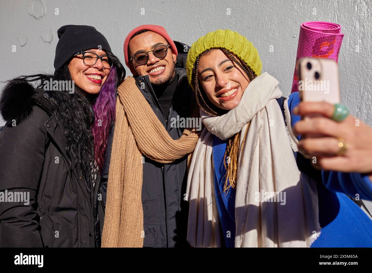 USA, New York City, Smiling friends in warm clothing taking selfie outdoors Stock Photo