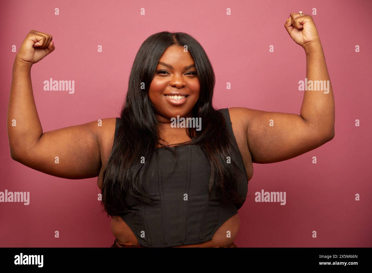 Studio portrait of woman flexing muscles against pink background Stock Photo
