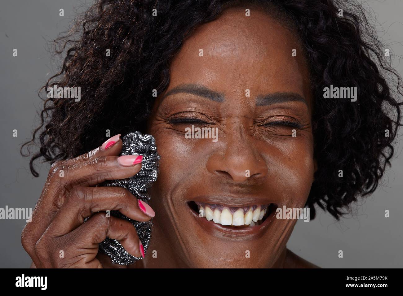 Studio portrait of mature woman holding scouring pad Stock Photo - Alamy