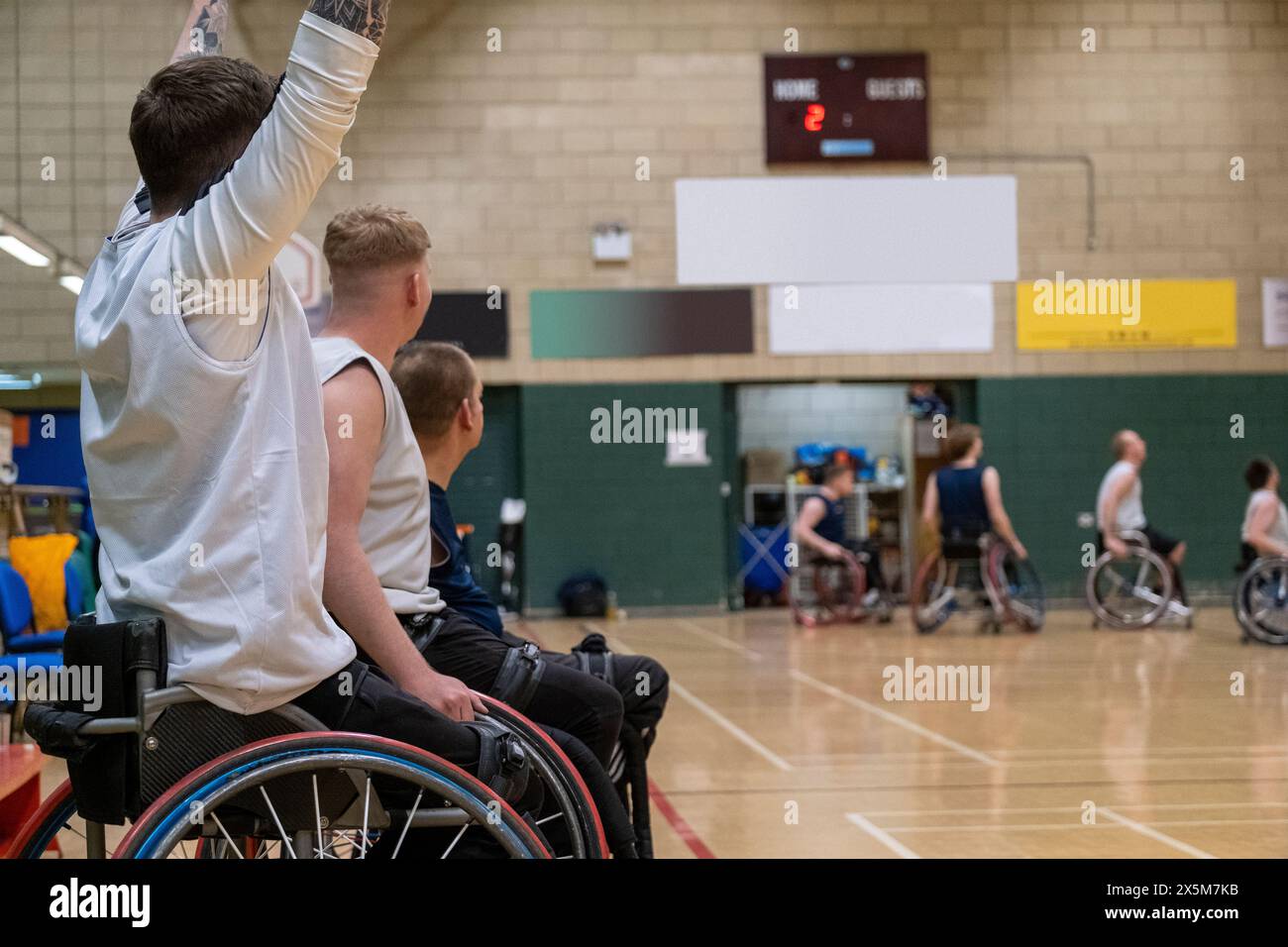 Male basketball players in wheelchairs cheering from sideline Stock