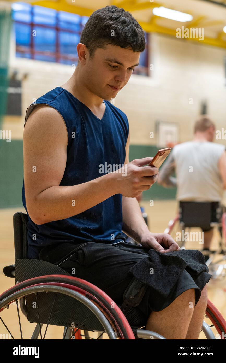 Male basketball player in wheelchair using smart phone Stock Photo