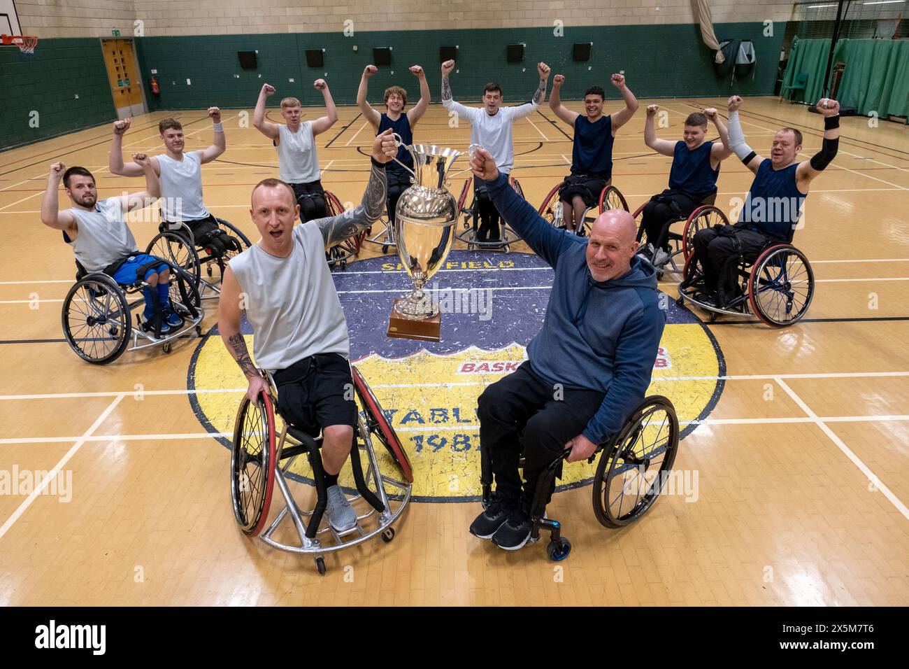 Team portrait of basketball players in wheelchairs with trophy Stock