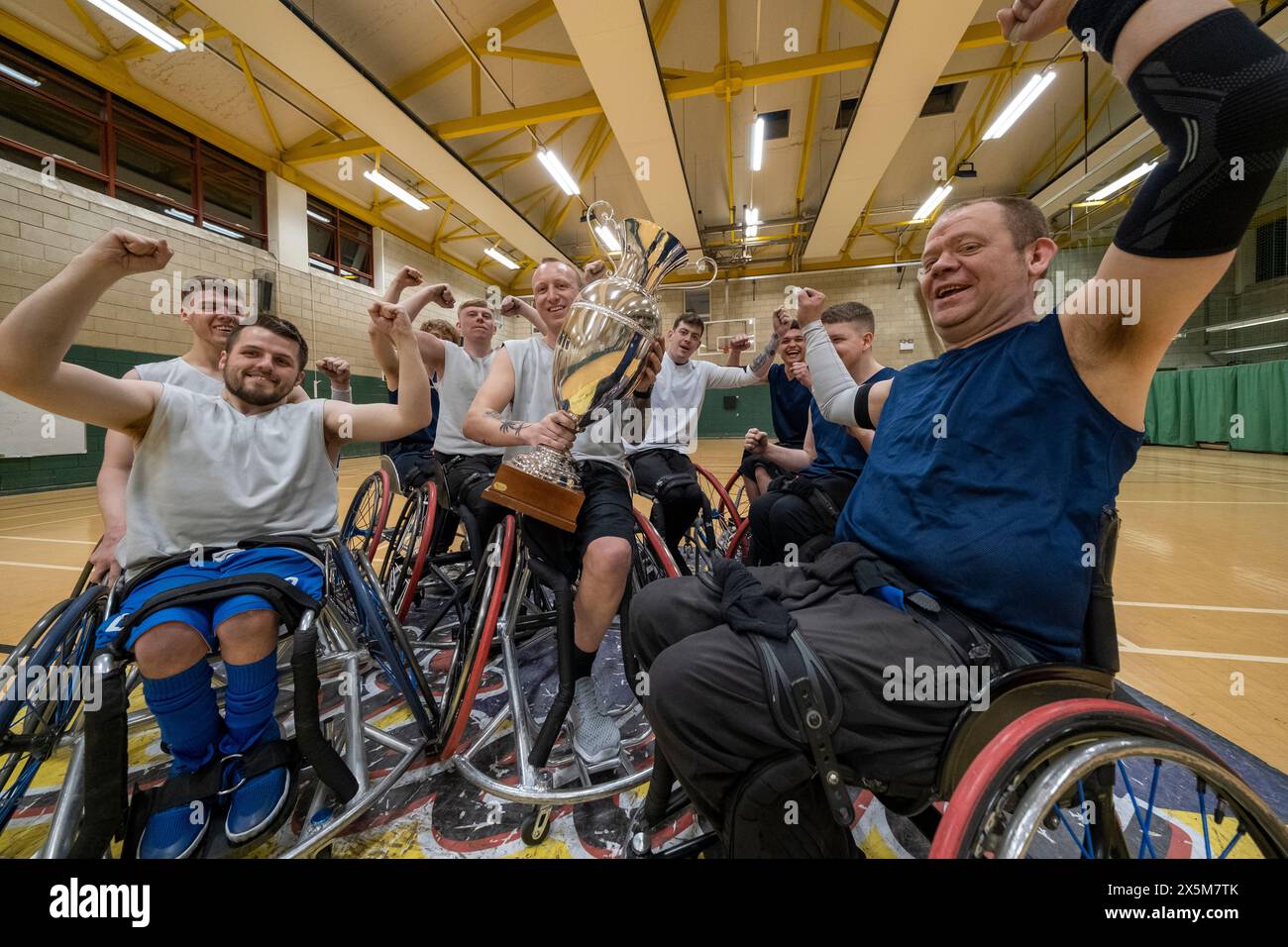 Team of basketball players in wheelchairs celebrating with trophy Stock
