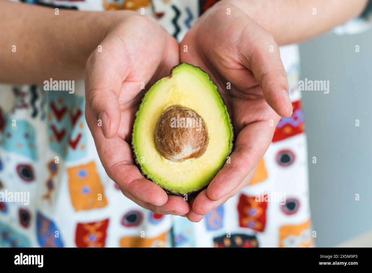 Hands holding ripe cut avocado Stock Photo - Alamy