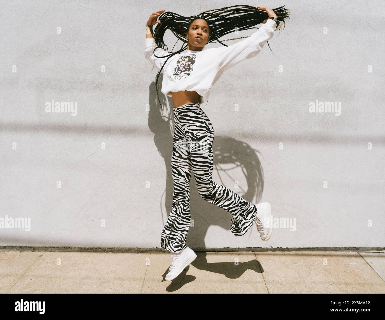 Young woman with long dreadlocks jumping Stock Photo