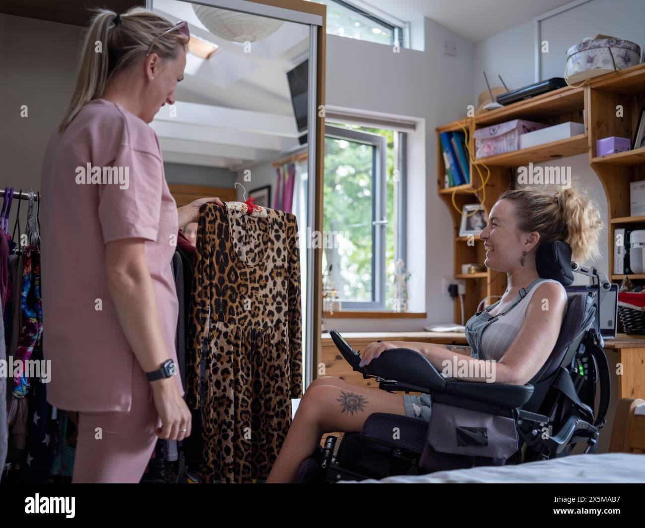 Assistant helping woman in wheelchair pick clothes Stock Photo - Alamy