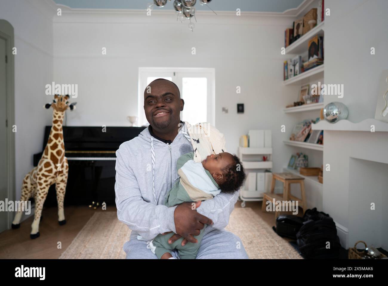 Man with Down syndrome holding baby boy (2-5 months) Stock Photo