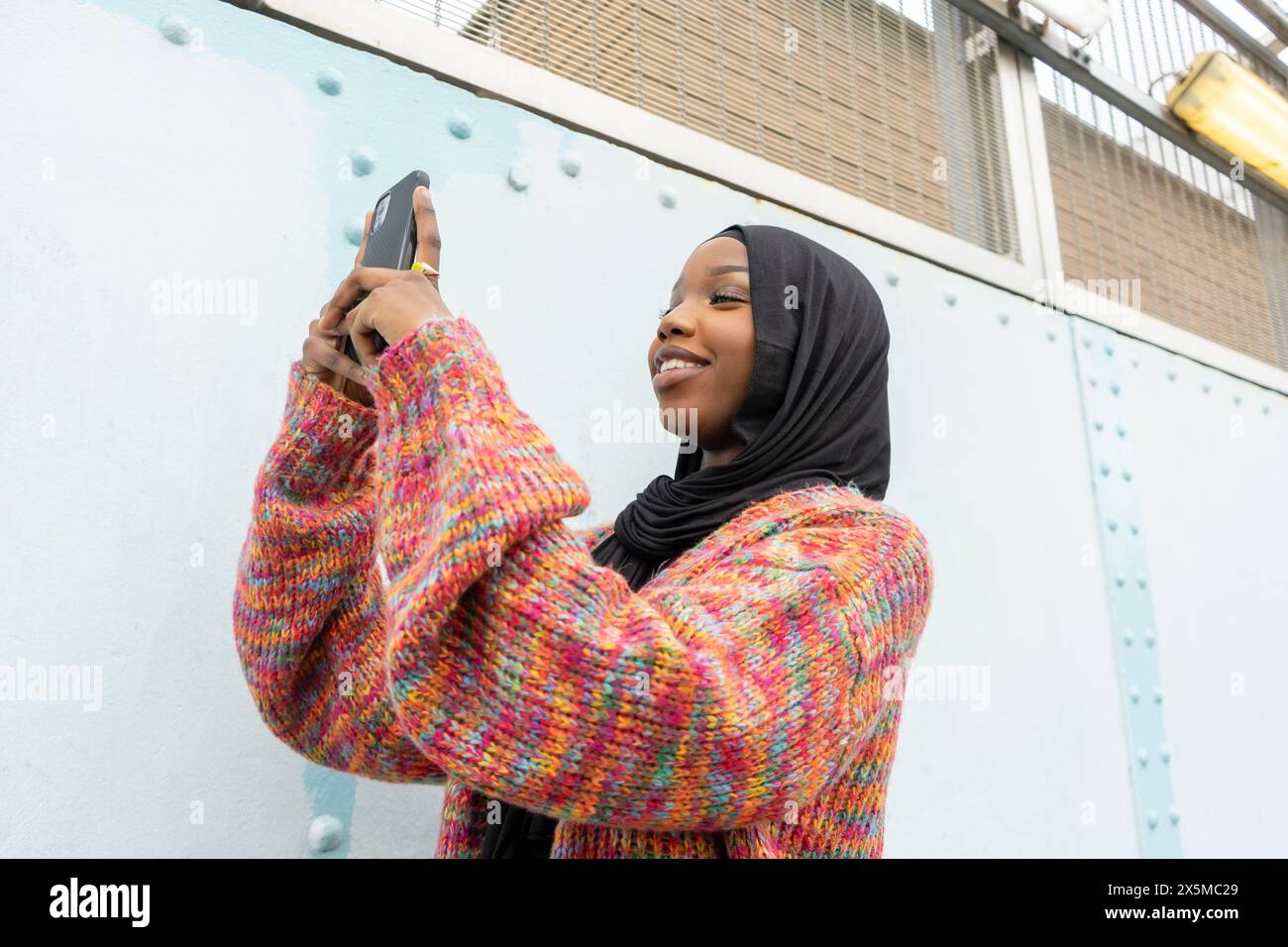 Smiling young woman wearing hijab taking selfie Stock Photo