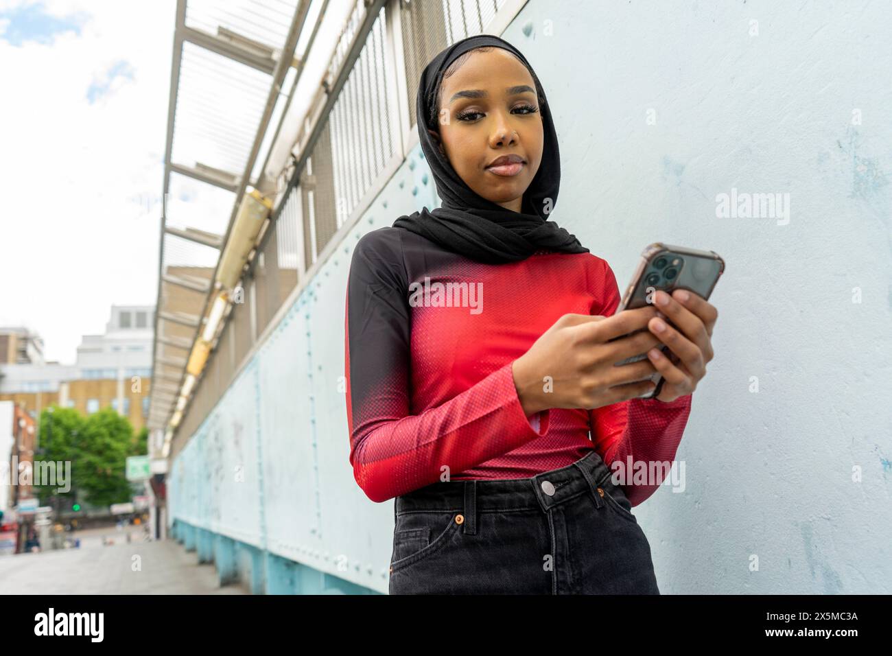 Portrait of young woman wearing hijab holding smart phone Stock Photo ...
