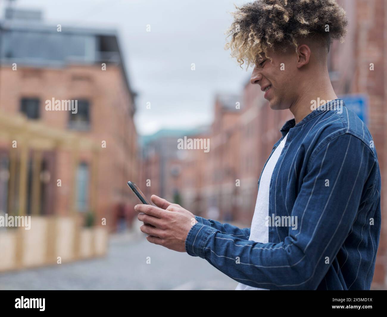 Smiling man using smart phone in city Stock Photo