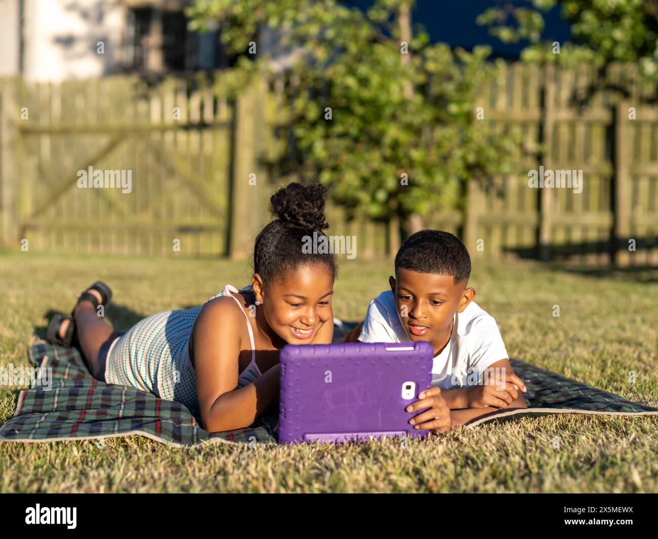 Siblings (8-9, 10-11) using tablet in back yard Stock Photo