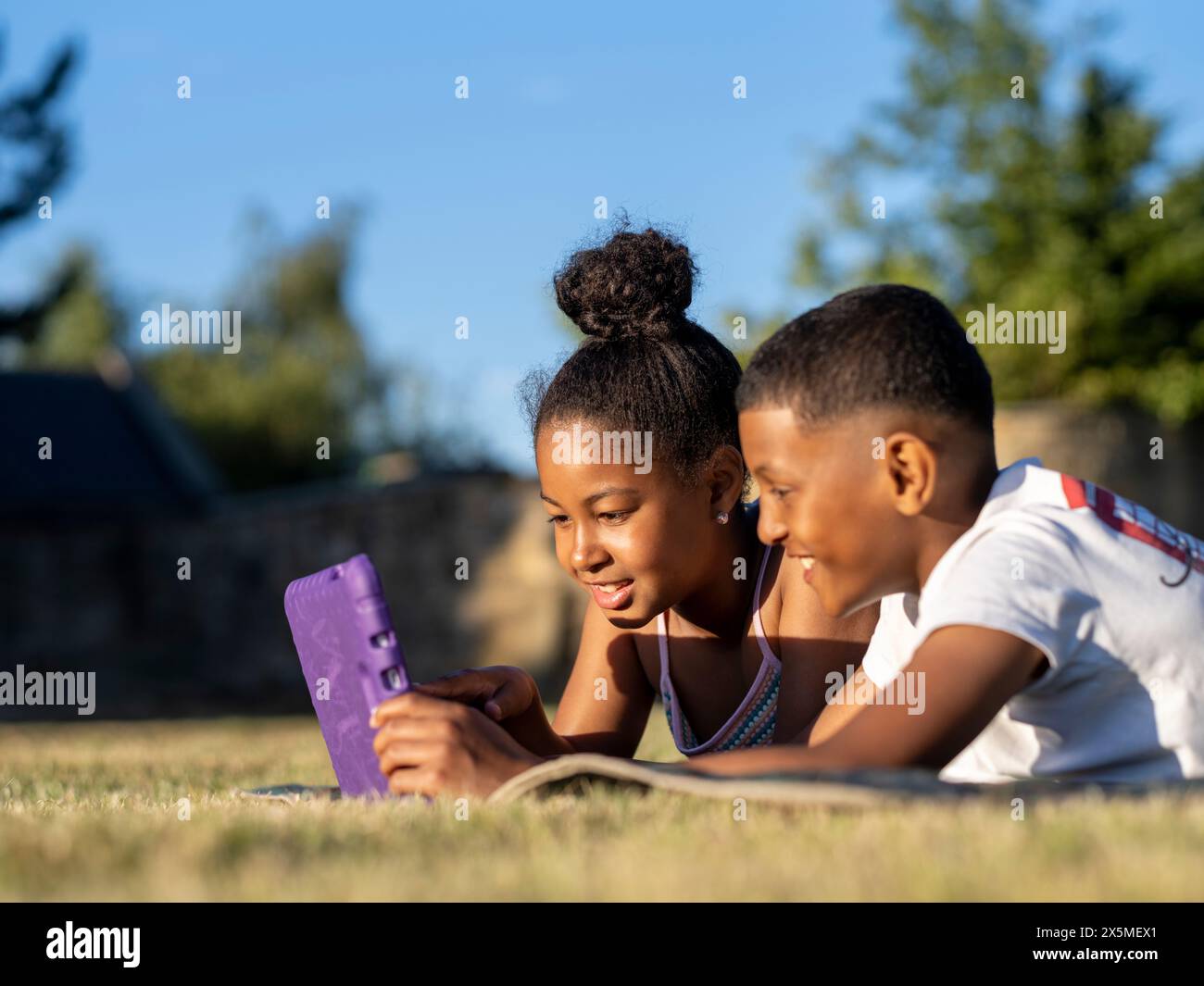Siblings (8-9, 10-11) using tablet in back yard Stock Photo
