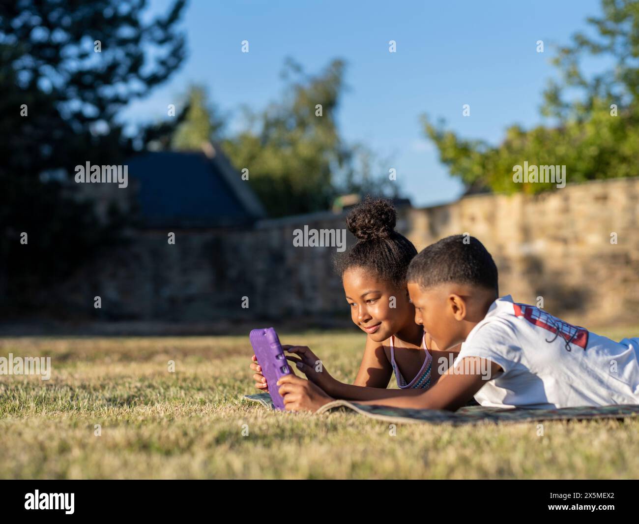 Siblings (8-9, 10-11) using tablet in back yard Stock Photo