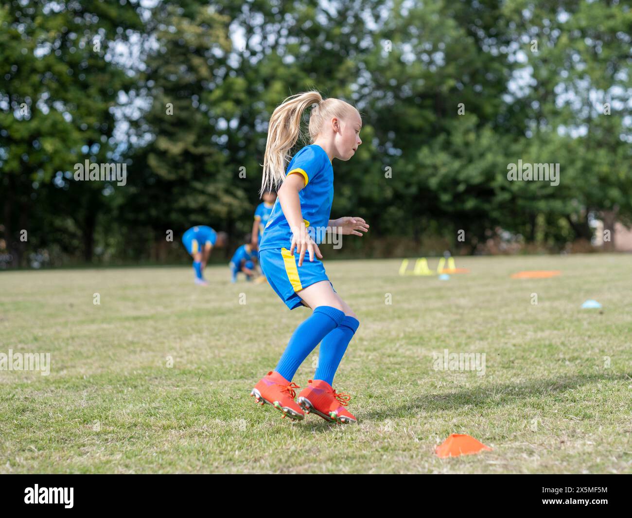 Girl (8-9) dressed in uniform practicing on soccer field Stock Photo