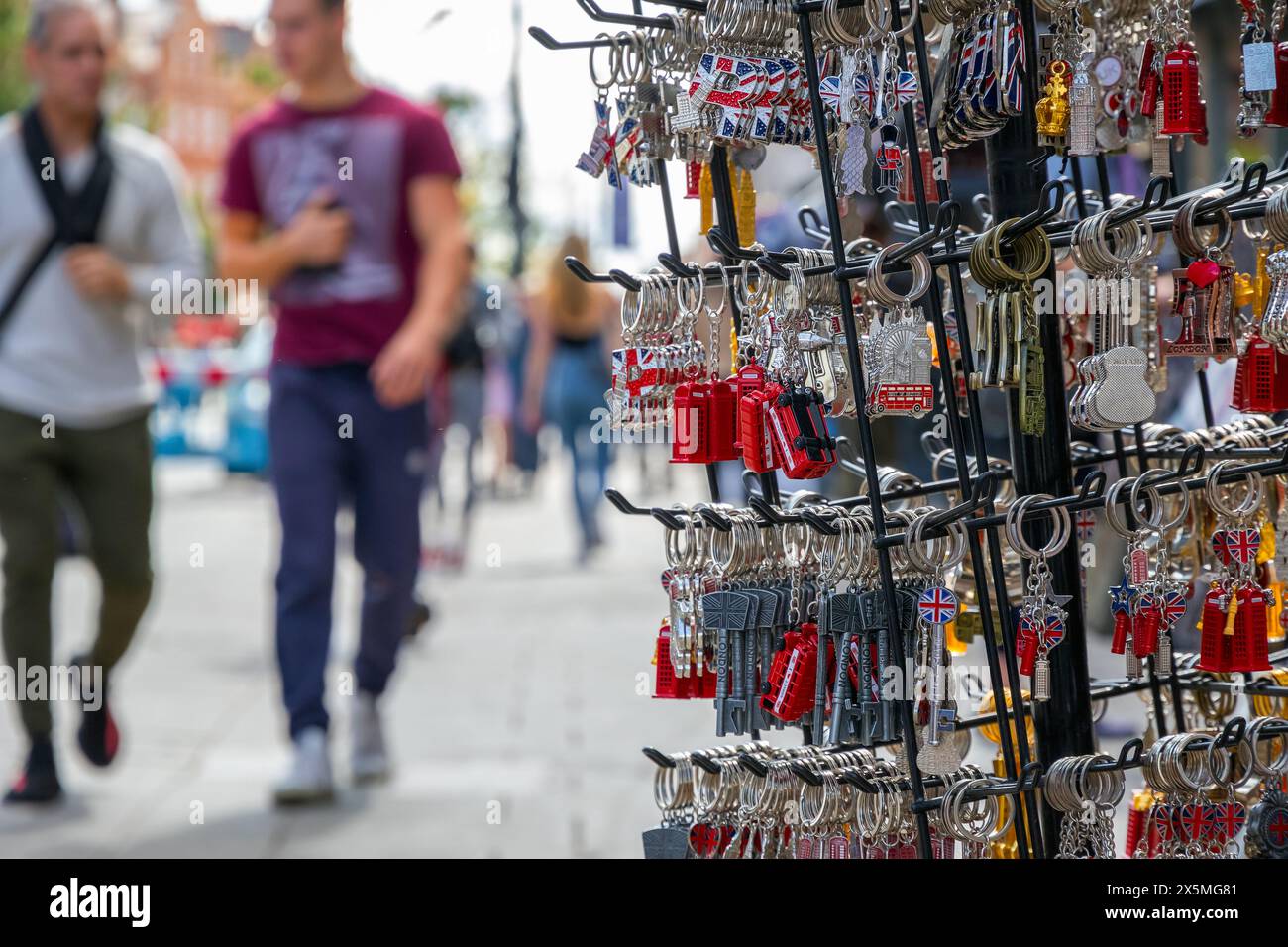 London keychain souvenir on display at Camden market with walking tourists in the background Stock Photo