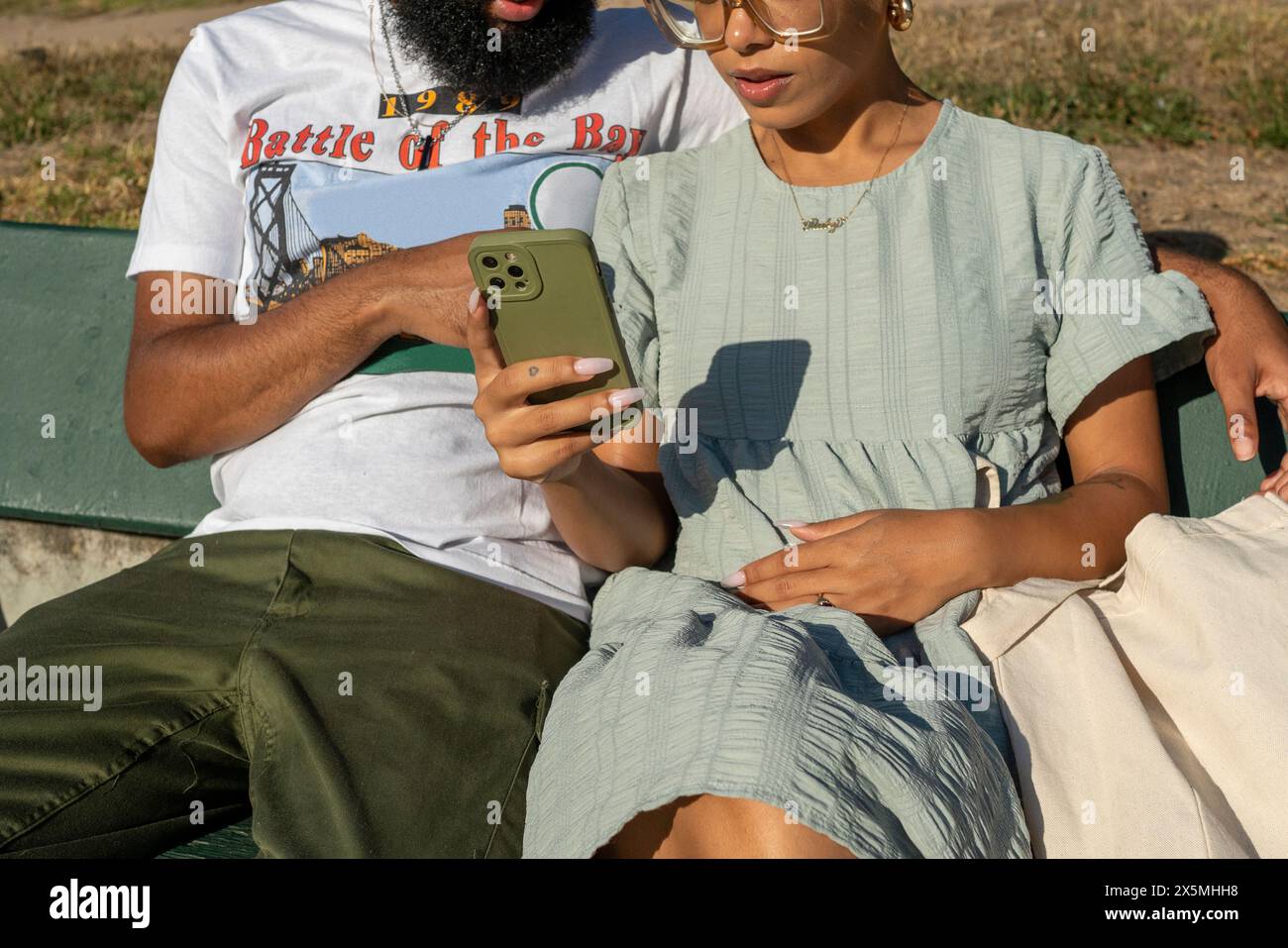 Couple sitting on bench and using smart phone Stock Photo