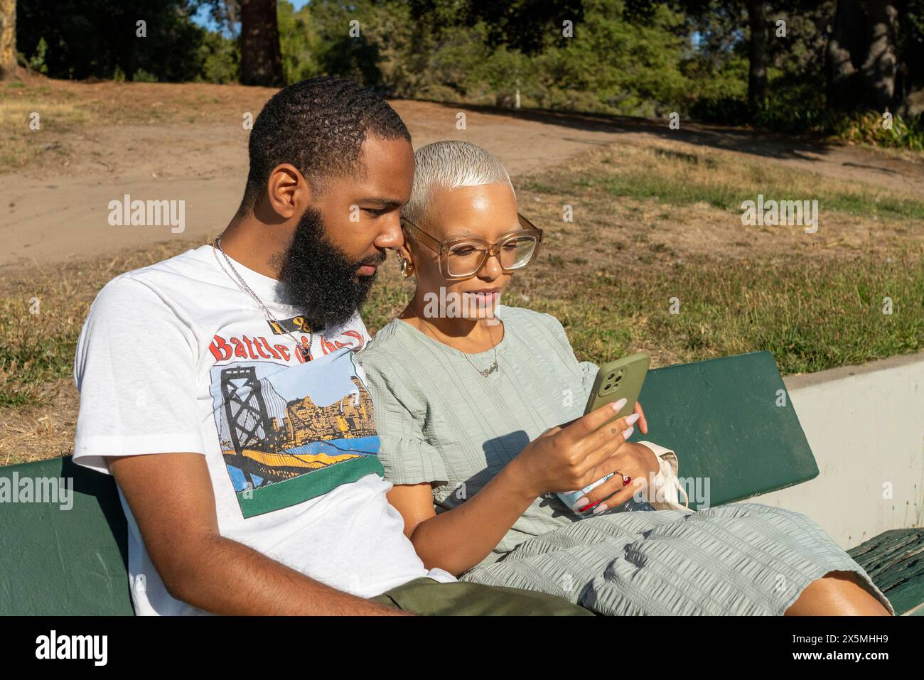 Couple sitting on bench and using smart phone Stock Photo
