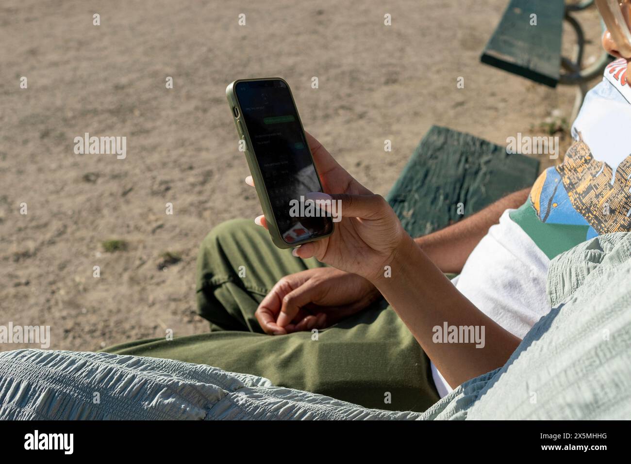Couple sitting on bench and using smart phone Stock Photo